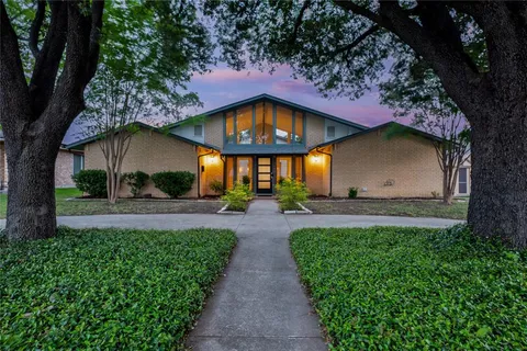 a view of a house with a small yard and a large tree