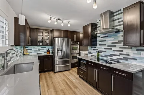 a kitchen with stainless steel appliances wooden cabinets a sink and a refrigerator