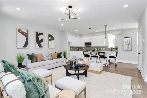 a kitchen with stainless steel appliances granite countertop a stove a sink a microwave a refrigerator and white cabinets with wooden floor