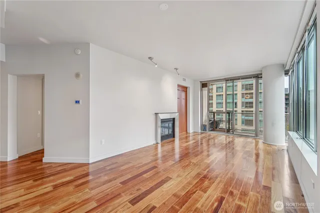 a view of an empty room with wooden floor and a window