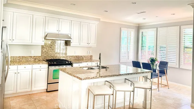 a kitchen with stainless steel appliances granite countertop sink stove and white cabinets with wooden floor