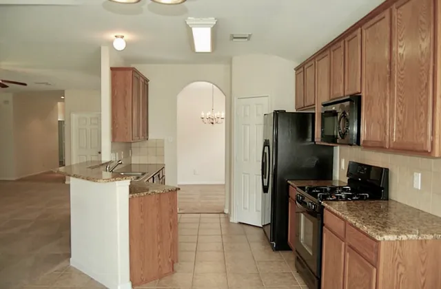 a kitchen with stainless steel appliances granite countertop a refrigerator a stove and a sink