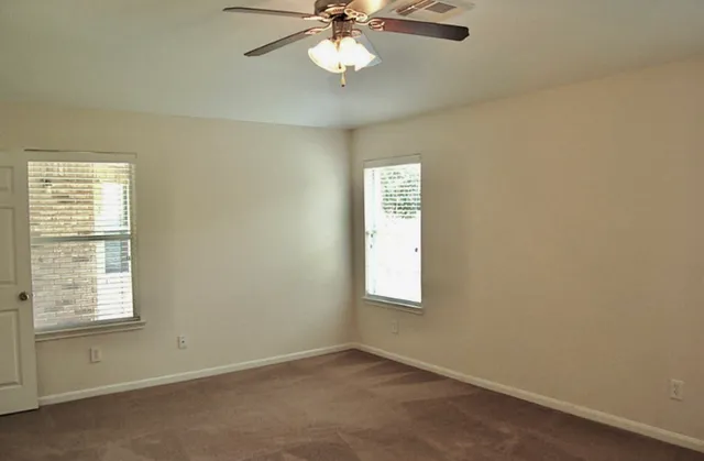 an empty room with a window and a ceiling fan