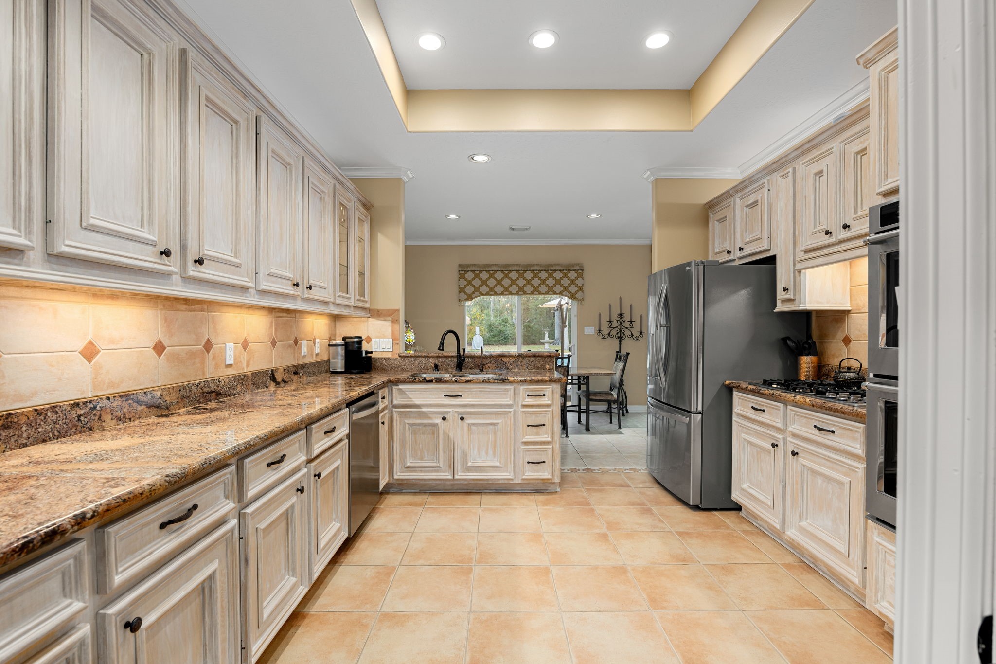 11984 White Oak Crossing Conroe, TX 77385 - Photo 15 of 42 Large kitchen with custom cabinet finish, granite counter tops, stainless steel appliances and bar area, great flow into the dining room and living room