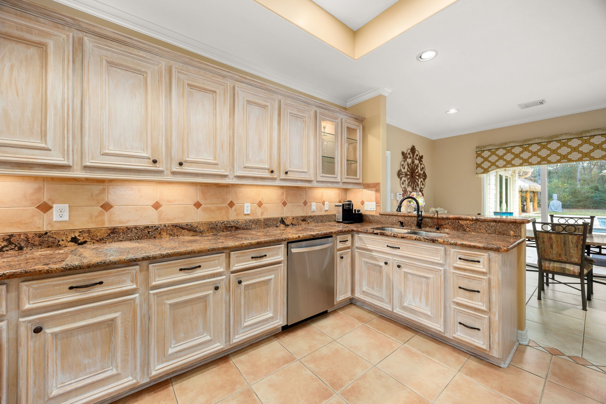 11984 White Oak Crossing Conroe, TX 77385 - Photo 16 of 42 Large kitchen with views to the pool area, custom cabinet finish, granite counter tops, stainless steel appliances and bar area, great flow into the dining room and living room