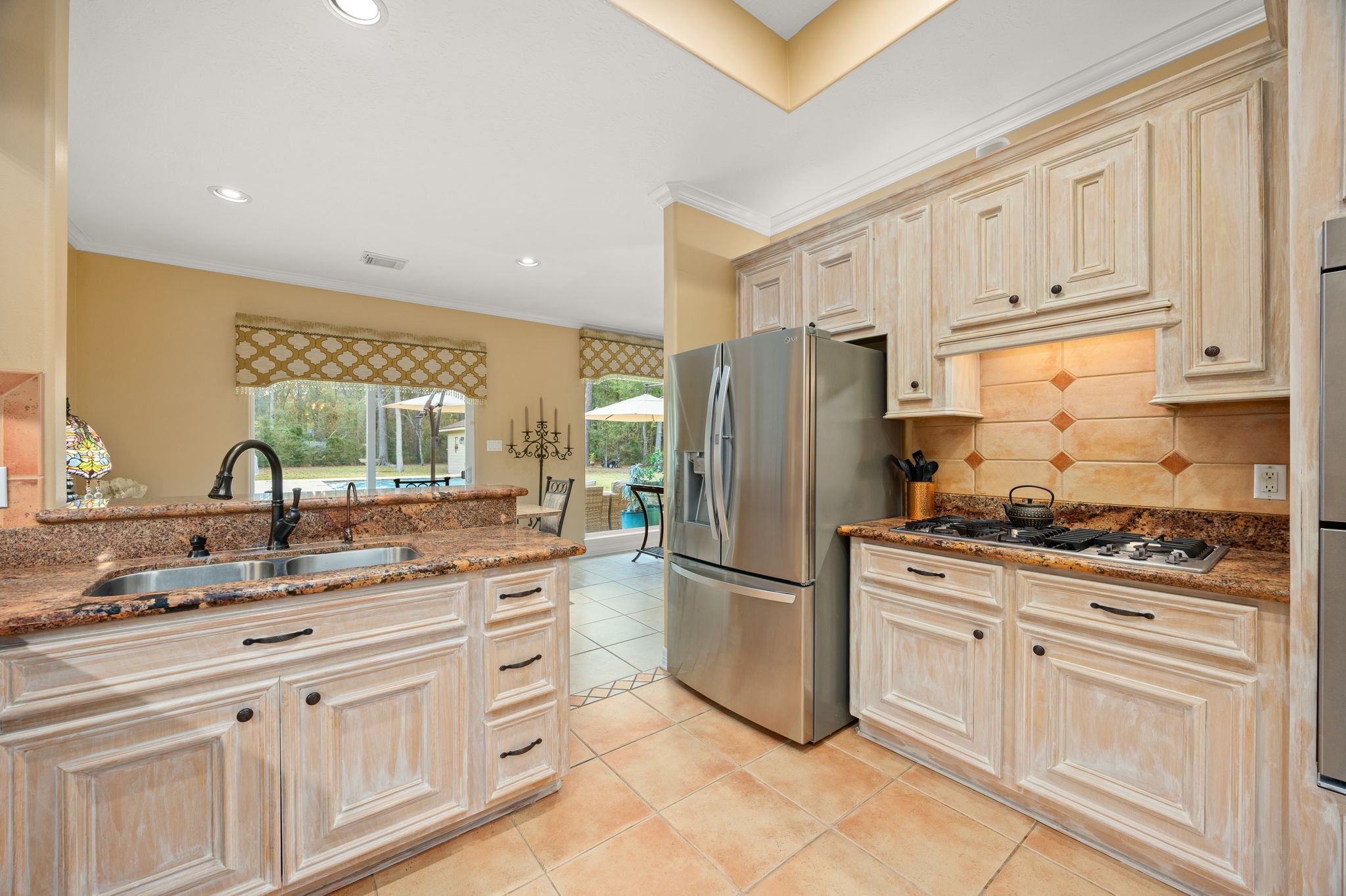 11984 White Oak Crossing Conroe, TX 77385 - Photo 17 of 42 Large kitchen with views to the pool area, custom cabinet finish, granite counter tops, stainless steel appliances and bar area, great flow into the dining room and living room