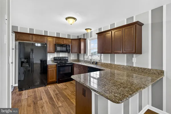 a kitchen with stainless steel appliances granite countertop a sink refrigerator and cabinets