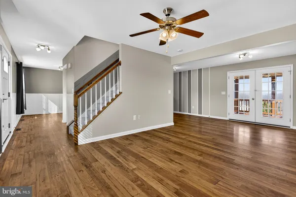 a view of an empty room with wooden floor and a ceiling fan