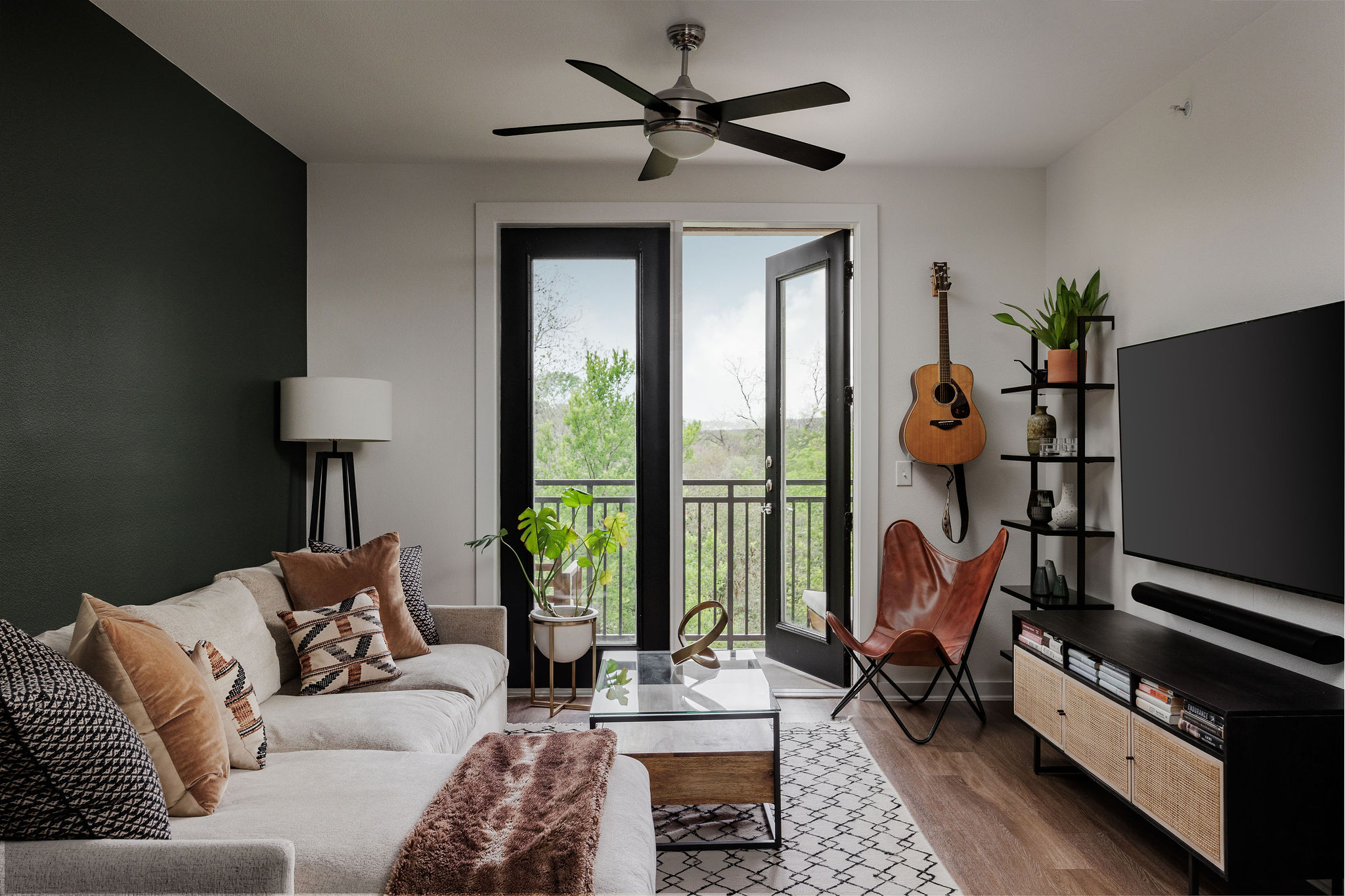 a living room with furniture a flat screen tv and a floor to ceiling window