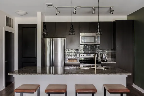 a kitchen with stainless steel appliances kitchen island granite countertop a refrigerator and a stove top oven