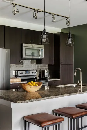 a kitchen with stainless steel appliances granite countertop a sink a stove and a wooden cabinets