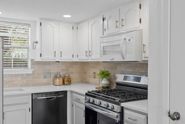 a kitchen with white cabinets and appliances