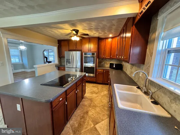 a large kitchen with kitchen island a large counter top space a sink a stove and a wooden floor