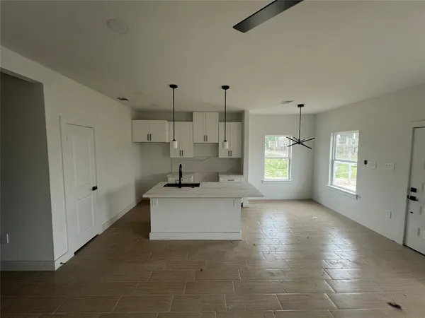 a large white kitchen with a window and refrigerator