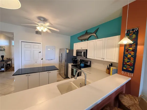 a kitchen with stainless steel appliances a sink dishwasher a microwave oven a stove with white cabinets and wooden floor