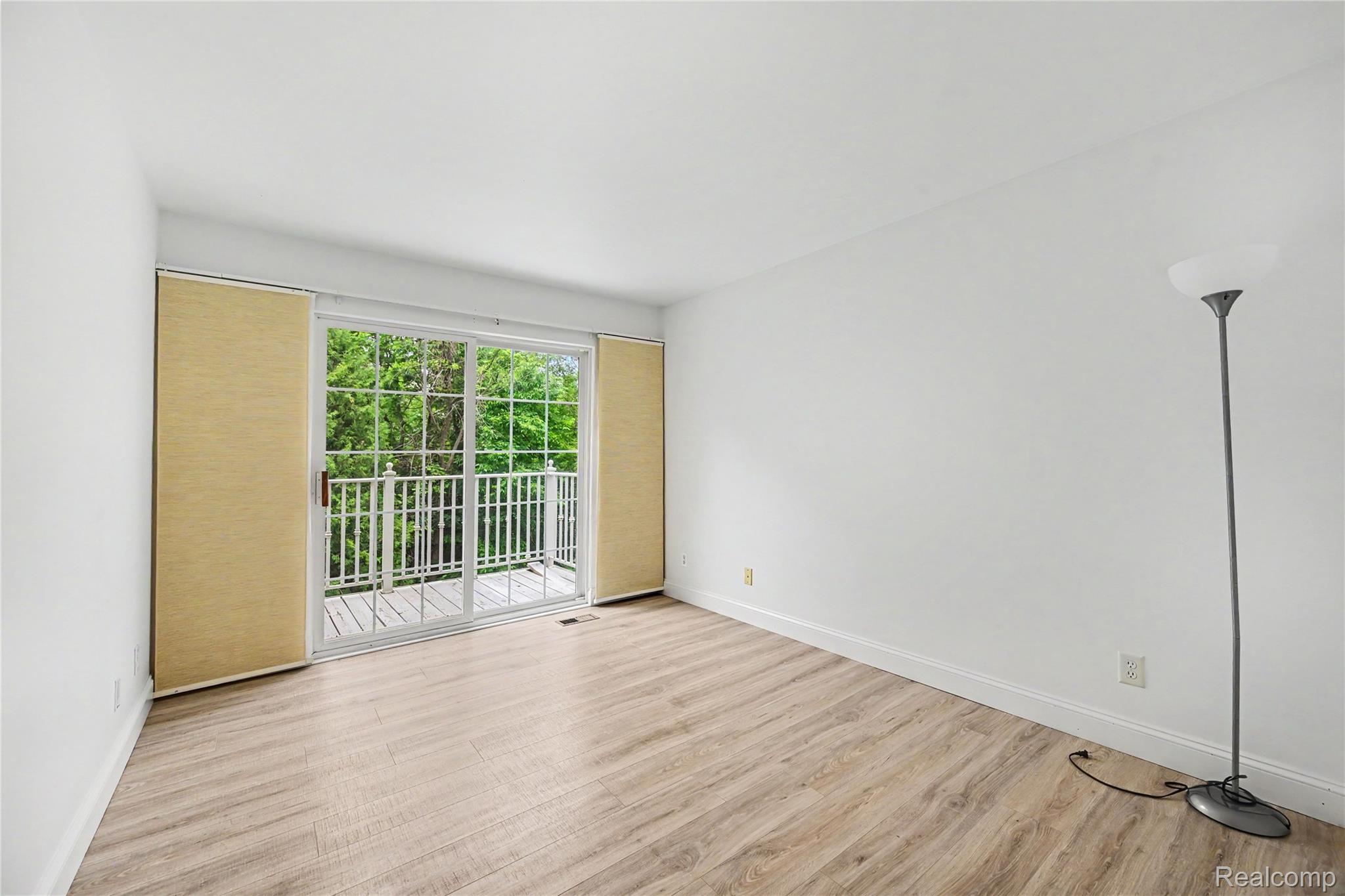 3633 Oakmonte Boulevard, Unit 189 Rochester, MI 48306 - Photo 28 of 36 Room featuring wood-finish flooring, white walls, and a sliding glass door leading to an outdoor balcony