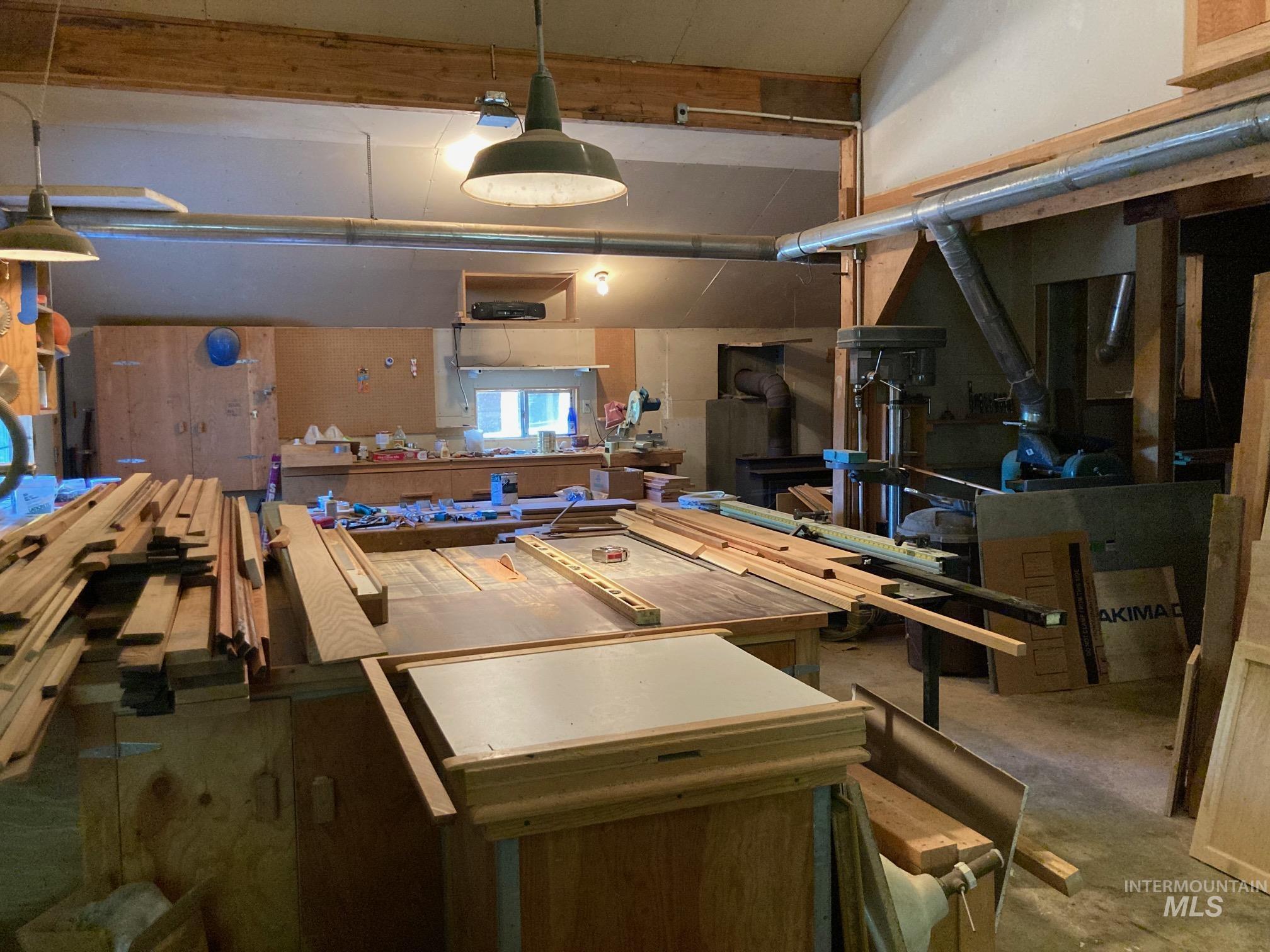 266 Falcon Ridge Road Kooskia, ID 83539 - Photo 43 of 50 Spacious workshop featuring exposed wood beams, industrial pendant lighting, built-in cabinetry, and integrated ductwork