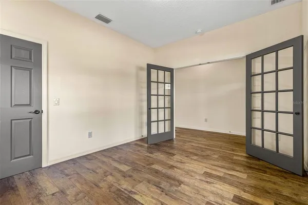 an empty room with wooden floor and windows
