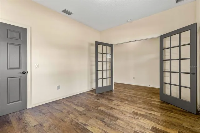 an empty room with wooden floor and windows
