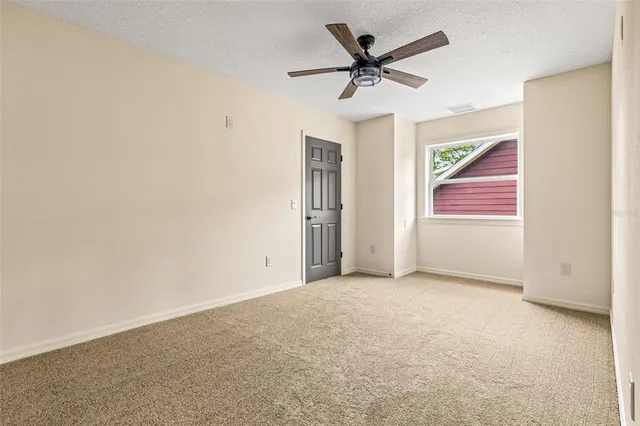 an empty room with window and ceiling fan