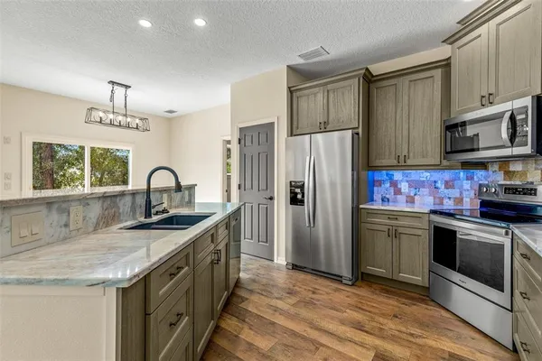 a kitchen with stainless steel appliances granite countertop a sink stove and refrigerator