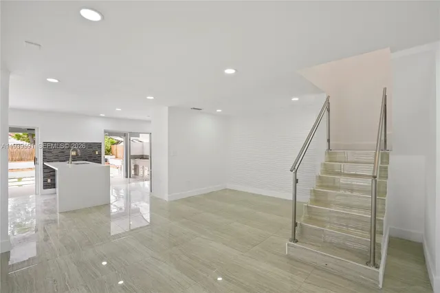 a view of kitchen with kitchen island granite countertop a refrigerator cabinets and a sink
