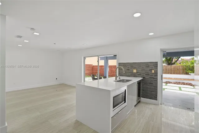 a large kitchen with stainless steel appliances kitchen island granite countertop a refrigerator and cabinets