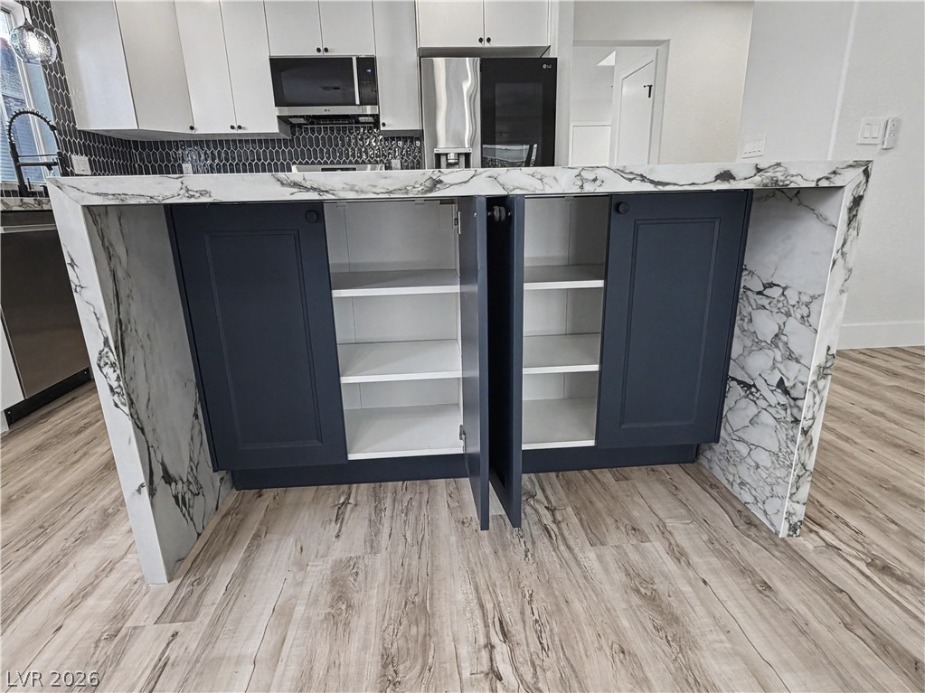8977 Paige Rene Court Las Vegas, NV 89117 - Photo 13 of 31 A contemporary kitchen island boasts ample storage with sleek, dark cabinetry and a striking marble waterfall countertop.