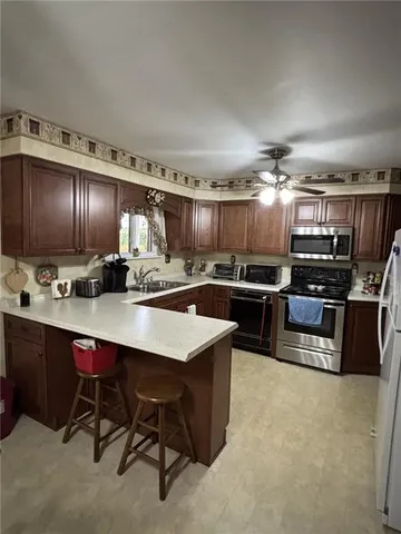 a kitchen with kitchen island stainless steel appliances a sink counter space cabinets and a couch