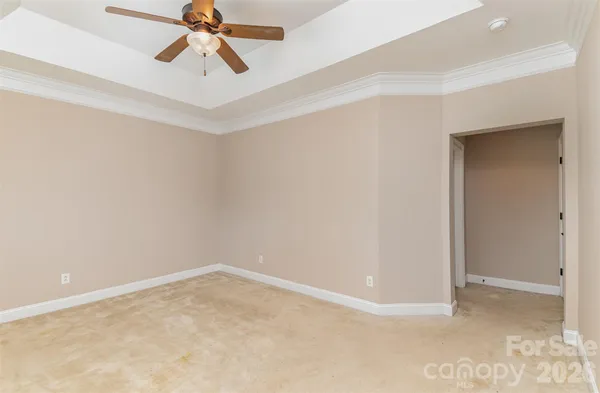 an empty room with a ceiling fan and carpet