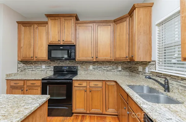 a kitchen with granite countertop a sink stove and cabinets