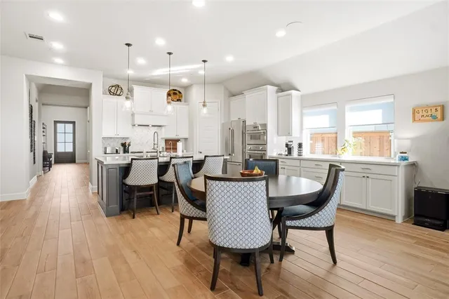 a dining room with stainless steel appliances a dining table wooden floor and a kitchen view
