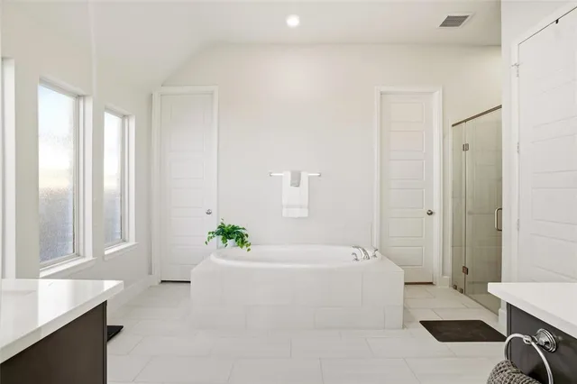 a white bath tub sitting in a spacious bathroom next to a window