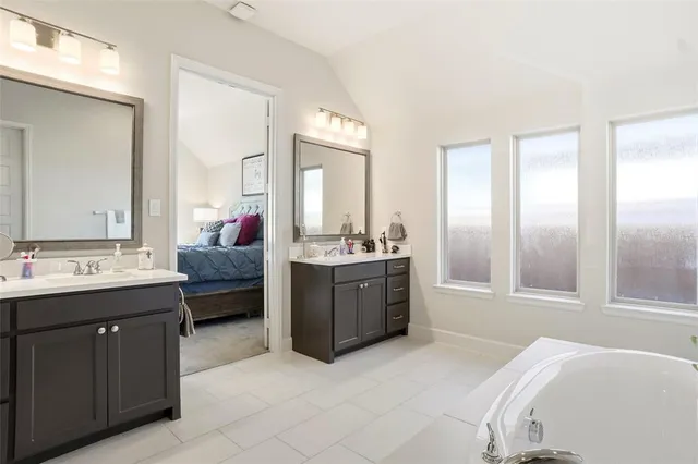 a bathroom with a tub sink vanity and mirror