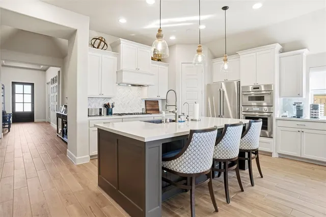 a kitchen with stainless steel appliances a dining table chairs a sink and a refrigerator