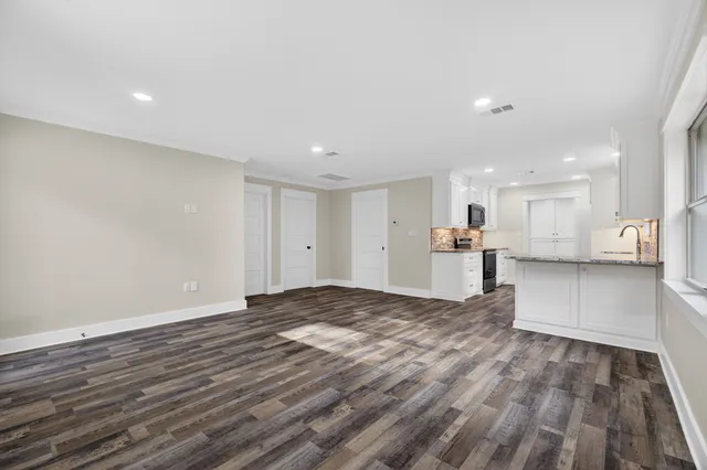 a view of an empty room with a window and wooden floor
