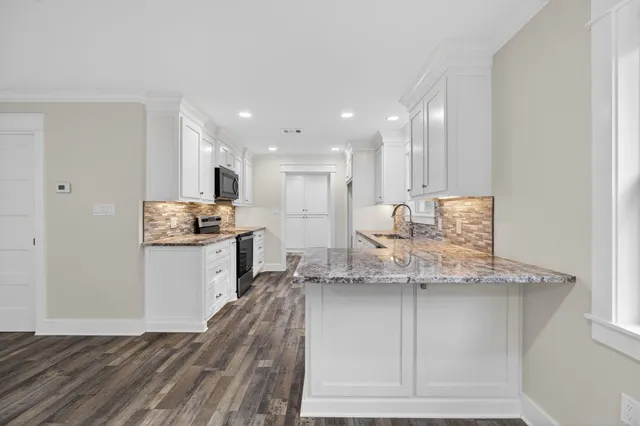 a kitchen with granite countertop cabinets stainless steel appliances and a wooden floor