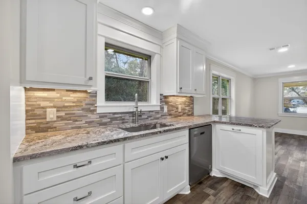a large kitchen with stainless steel appliances granite countertop wooden cabinets a stove top oven a sink and dishwasher