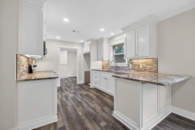 a kitchen with granite countertop a sink stove and cabinets