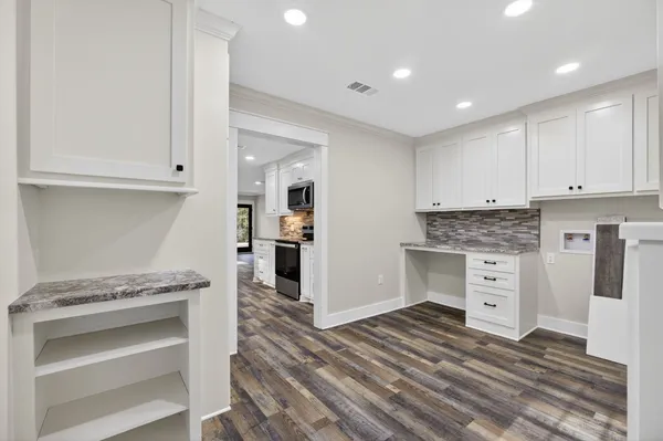 a view of a kitchen with white cabinets and stainless steel appliances
