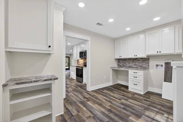 a view of a kitchen with white cabinets and stainless steel appliances