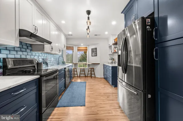 a kitchen with stainless steel appliances granite countertop a refrigerator a stove and a sink