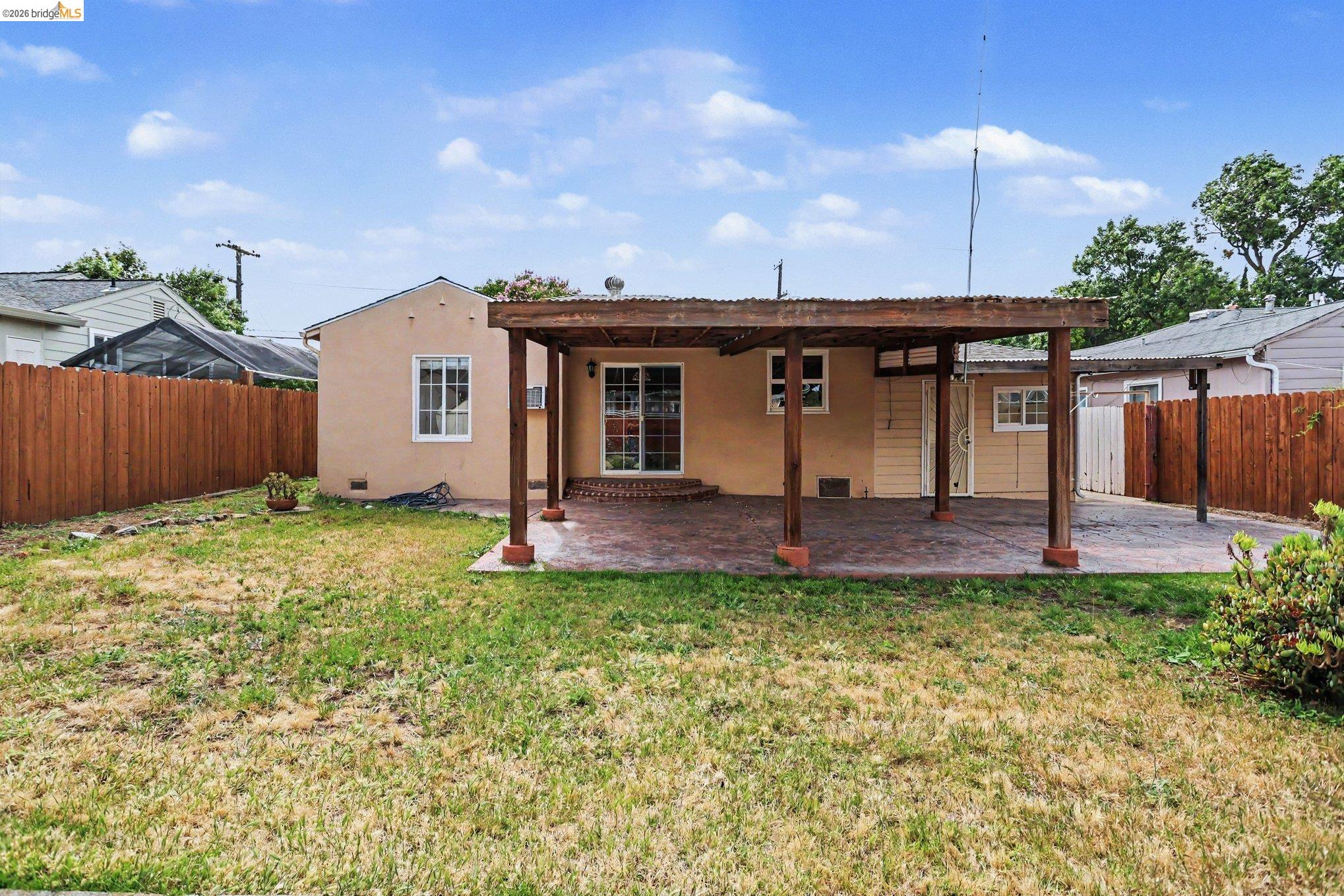 249 Madison Avenue Bay Point, CA 94565 - Photo 16 of 18 Backyard featuring a covered patio with a stamped concrete surface, a stucco exterior, sliding glass doors, and a wood privacy fence