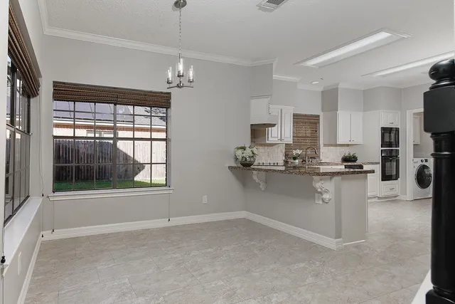 a kitchen with white cabinets and window