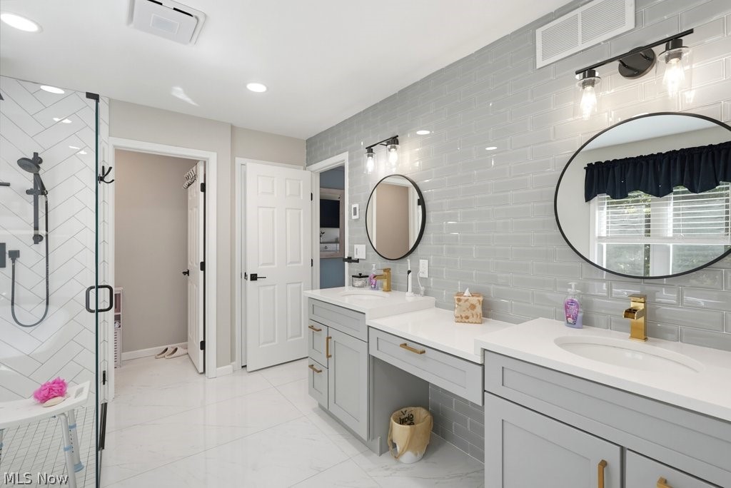 851 Susan Road Ravenna, OH 44266 - Photo 32 of 50 Dual vanity with quartz countertops, custom cabinetry, large round mirrors, and an expansive walk-in shower with a glass enclosure and herringbone tile