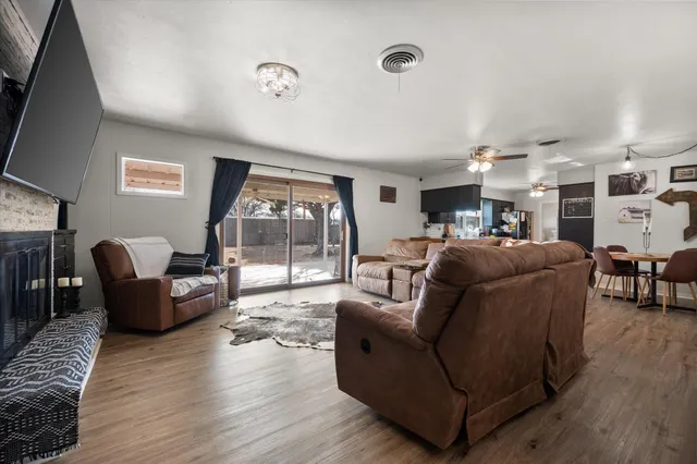 a living room with furniture a large window and wooden floor
