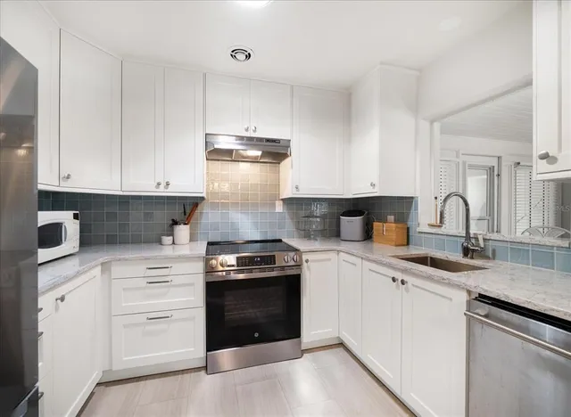 a kitchen with granite countertop white cabinets and appliances