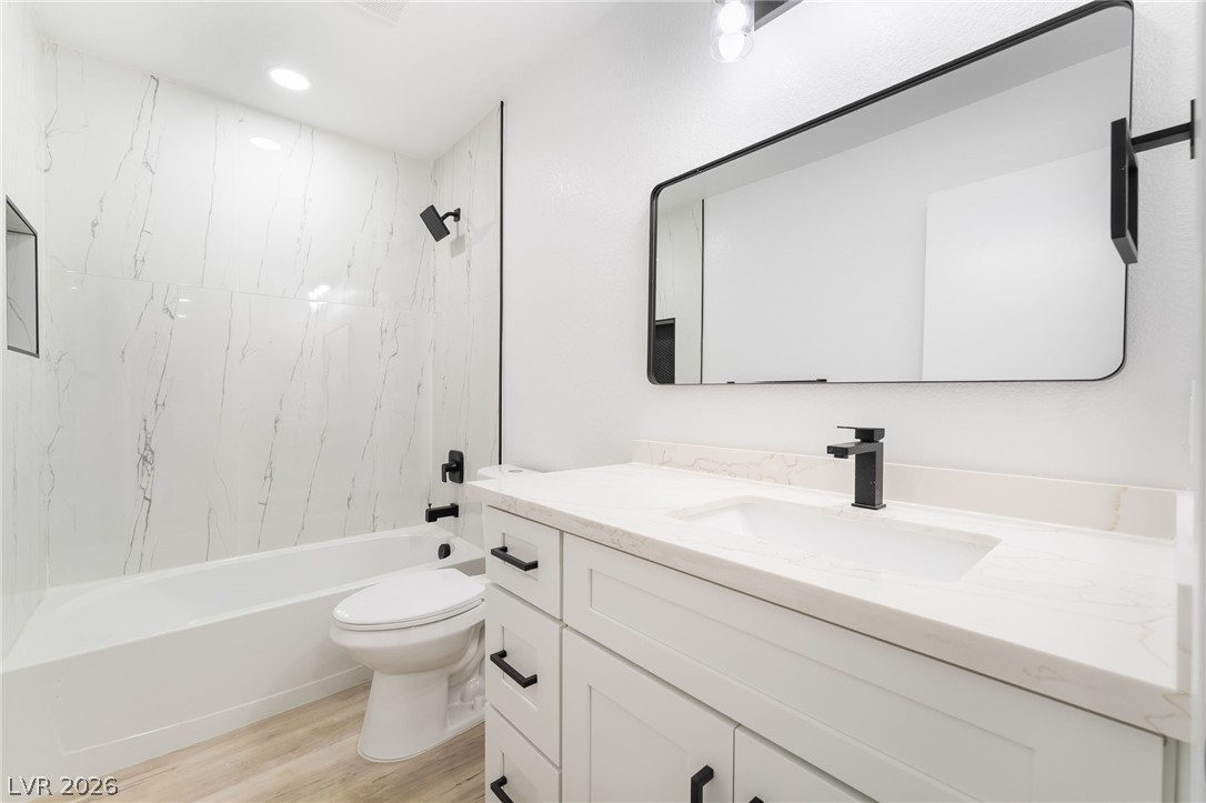 39 Lowery Street Henderson, NV 89015 - Photo 22 of 40 A refined bathroom features a crisp white vanity, sleek dark fixtures, and striking marble-patterned tile work.