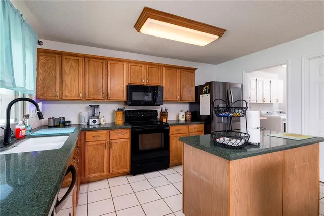 a kitchen with stainless steel appliances granite countertop a stove top oven a sink dishwasher and a refrigerator with wooden cabinets