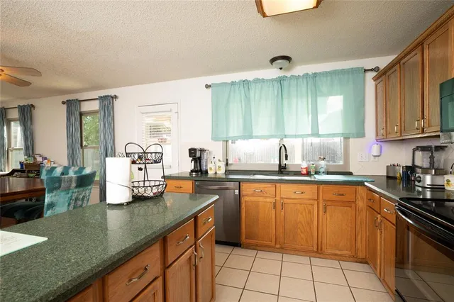 a kitchen with granite countertop a sink dishwasher stove and cabinets